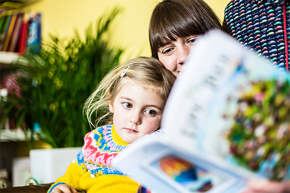 Young girl reading Life Tree book with mother